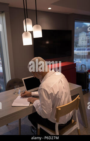 Imprenditore prendendo appunti su un notebook Foto Stock