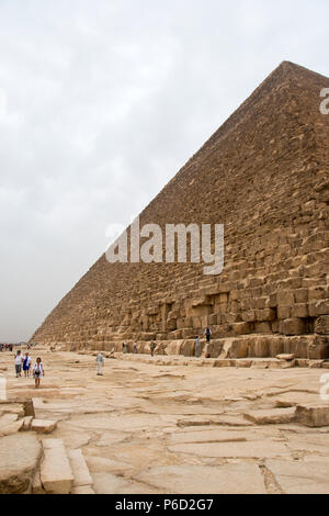 I turisti a piedi intorno alla base della Grande Piramide di Giza (piramide di Khufu, piramide di Cheope) di Giza in Egitto. Foto Stock