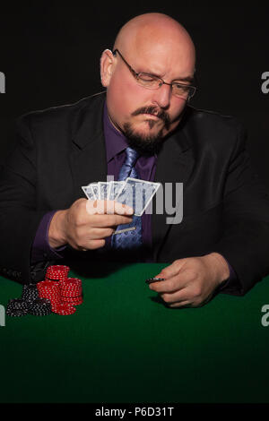 Scheda giocatore in business suit. Bicchieri e cravatta con chip di gioco su sfondo nero. Foto Stock