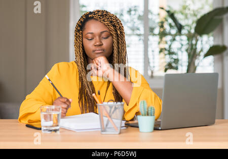 African American donna studiando con laptop faccia seriamente pensando di domanda, molto confusa idea Foto Stock