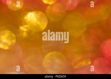Abstract irridescent rossa e dorata sfondo bokeh, incandescente cerchi. Foto Stock