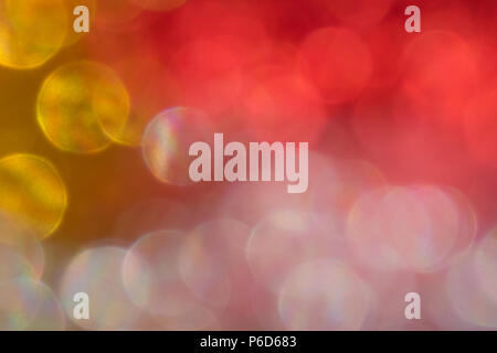 Abstract irridescent rossa e dorata sfondo bokeh, incandescente cerchi. Foto Stock