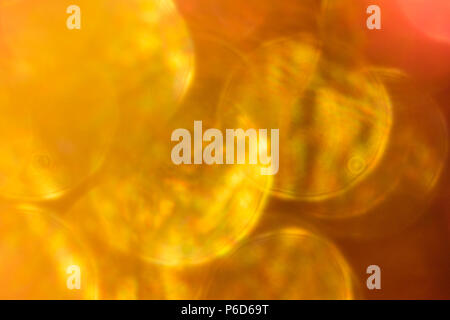 Abstract irridescent rossa e dorata sfondo bokeh, incandescente cerchi. Foto Stock
