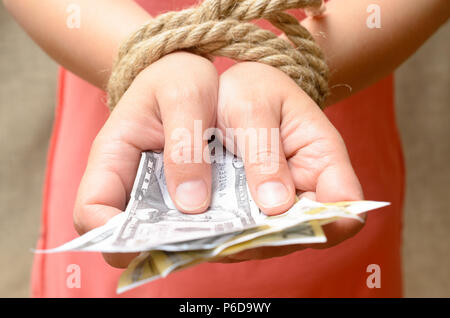 Le mani delle donne legato con una corda e tenendo il denaro. Bondage di credito. Foto Stock