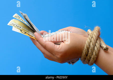 Le mani delle donne legato con una corda e tenendo il denaro. Bondage di credito. Foto Stock