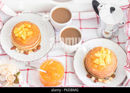 Tradizionale e romantica la prima colazione per due in un vassoio. American pancake con marmellata di arancia e i dadi sulle piastre di vintage e bianco 2 tazze di caffè con me italiano Foto Stock