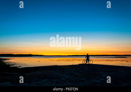 Ardara, County Donegal, Irlanda meteo. Il 29 giugno 2018. Un ciclista orologi il tramonto su Irlanda 'Wild Atlantic modo' alla fine di una calda giornata estiva sulla costa nord-occidentale. Credito: Richard Wayman/Alamy Live News Foto Stock