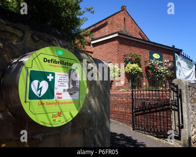 Per salvare la vita defibrillatore montato sul villaggio locale parete hall in Bramly, South Yorkshire Foto Stock