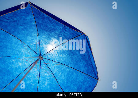 Spiaggia blu parasolo contro cielo blu soleggiato e in contre-jour con spazio copia Foto Stock