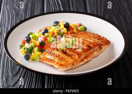 Appena cotta alla brace di filetto di salmone con pepe, mais, mirtillo e insalata di cipolla close-up su una piastra su un piano orizzontale. Foto Stock