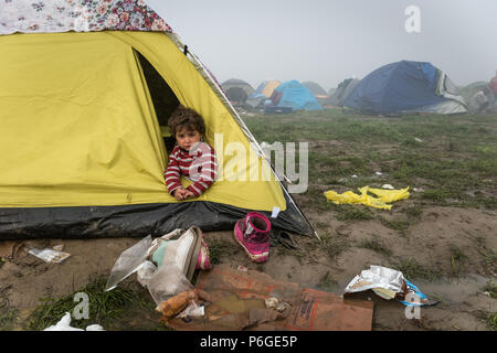 Un giovane bambino guarda fuori da una tenda al campo di fortuna della frontiera Greek-Macedonian vicino al villaggio greco di Idomeni. Foto Stock