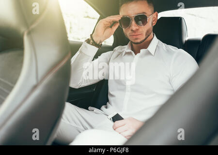 Imprenditore belli seduti in auto di lusso sul sedile posteriore Foto Stock