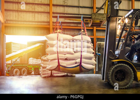 Carrello di movimentazione dello zucchero bianco sacchi per il ripieno in contenitori al di fuori di un magazzino. Distribuzione, Logistica Import Export, concetto di magazzino. Foto Stock