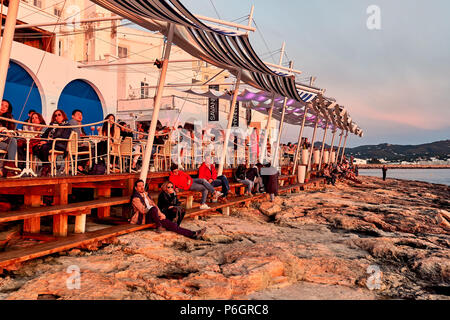 Isola di Ibiza, Spagna - 1 Maggio 2018: una folla di gente che soddisfano il tramonto dalla terrazza fronte mare di Cafe Del Mar. Questo luogo è famoso per le viste al sole Foto Stock