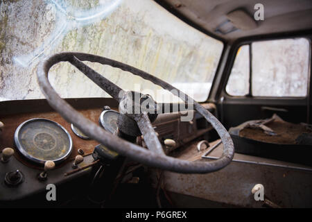 Un vecchio abbandonato vintage auto a sinistra fuori nei boschi. Soffre di decadimento e ruggine. Foto Stock