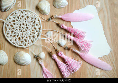 Seashells telaio su sfondo di legno con posto per il testo. Carta per un party in spiaggia, invito, pubblicità.Dreamcatcher con piume rosa Foto Stock