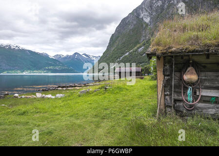 Vecchio boathouse presso la riva del Norddalsfjorden, Norvegia, vecchia baita in legno con panorama del fiordo e delle montagne Foto Stock