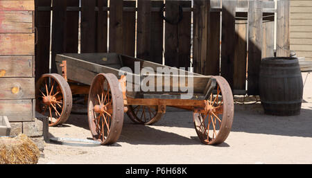Carro di legno costruita su un telaio in acciaio con ruote in acciaio parcheggiato a fianco di un asse di legno edificio con un recinto in legno e botte di rovere in background Foto Stock