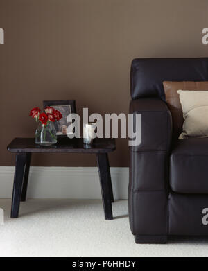 Piccolo rustico tavolo in legno accanto al divano in pelle nera nella moderna mid-marrone di soggiorno Foto Stock