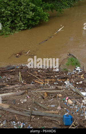 Tutti i tipi di umana prodotta dai detriti, come bottiglie di plastica e rami, legno e fango intasare e inquinare un fiume dopo un allagamento Foto Stock