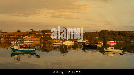 Tramonto sul piatto di calme acque del porto castletownshend, Irlanda, con una miscela di imbarcazioni al punto di ancoraggio. Foto Stock