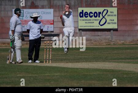 Un bowler veloce in azione a Glossop cricket club Foto Stock