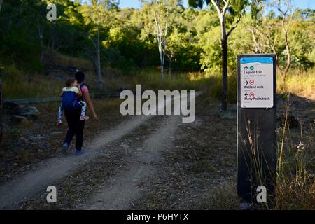 Madre e bambini a piedi passato un segno su sterrato, molti picchi di escursione al Monte Marlow, città di Townsville Queensland comune, 4810, Australia Foto Stock