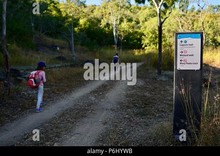 Madre e bambini a piedi passato un segno su sterrato, molti picchi di escursione al Monte Marlow, città di Townsville Queensland comune, 4810, Australia Foto Stock