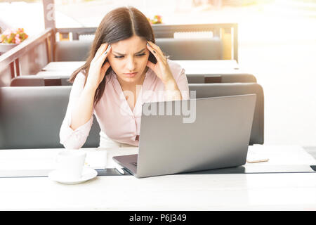 Giovane e bella donna d'affari stanchi di lavorare in ufficio. Donna che mantiene la sua testa Foto Stock