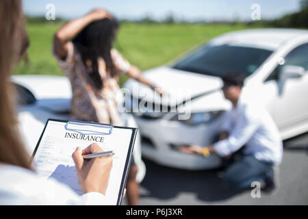 Vista laterale della scrittura sulla clipboard mentre agente di assicurazione auto esame dopo un incidente Foto Stock