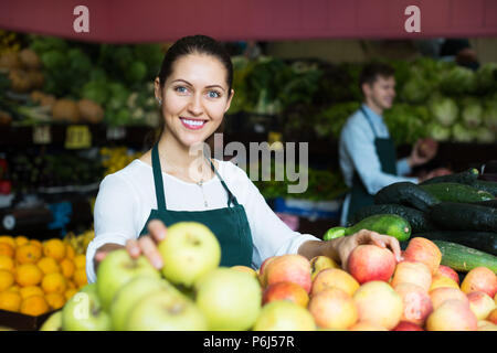 Ragazza sorridente roba in vendita della catenaria dolce di mele stagionale al marketplace Foto Stock