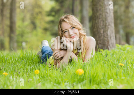 Pretty Woman sdraiato sul campo di tarassaco felice allegro ragazza in appoggio sul prato di tarassaco, relax all'aperto in primavera, vacanze Foto Stock