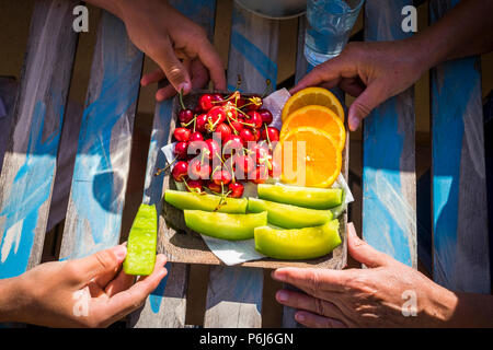 Primo piano di giovani e vecchie mani da nonna e adolescente nipote di mangiare alcuni freschi frutti di stagione sulla tavola di legno. healhty stile di vita in famiglia Foto Stock