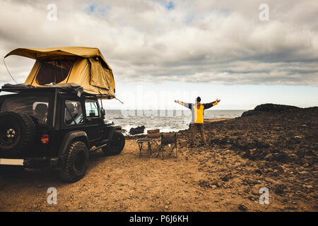 Adventurer uomo in viaggio viaggi con off road Auto e tenda sul tetto per godere della libertà e explorer concetto. Scoprite il mondo che vive vicino alla potenza del th Foto Stock