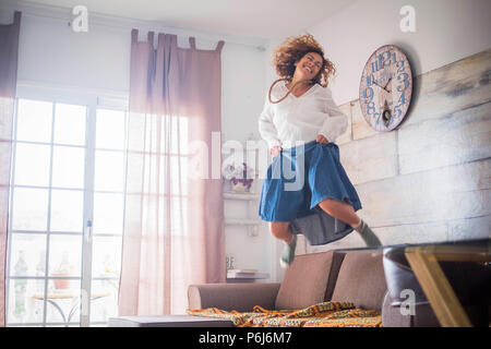 Lonely crazy bella donna di mezza età jumping a casa per la soddisfazione o la vittoria. sorriso molto e hanno funwith un grande salto sul divano. Libertà e Foto Stock