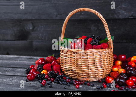 Freschi frutti di bosco in cesto su un tavolo di legno. Spazio di copia Foto Stock