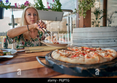 Ragazzina prende un trancio di pizza dalla tabella Foto Stock