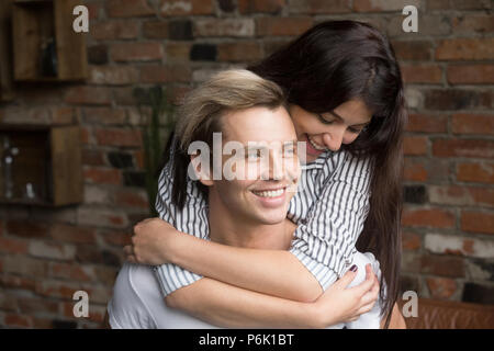 Felice ragazza sorridente piggyback fidanzato divertirsi a casa Foto Stock