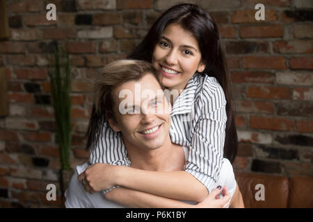 Ritratto di felice coppia millenario abbracciando in posa per la famiglia al Foto Stock