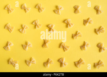 Farfalle di pasta su sfondo giallo, vista dall'alto, piatto laici. Foto Stock