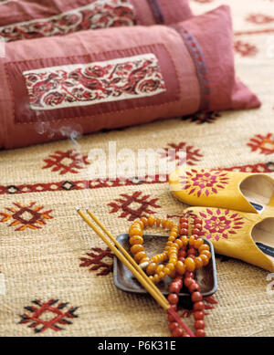 Close-up di cuscini rosa e gioielli su modellato sisal rug Foto Stock