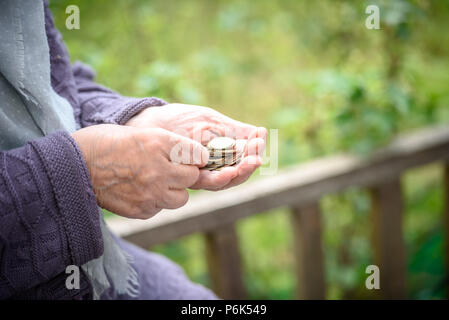 Soldi, monete, la nonna in materia di pensioni e di un concetto di un soggiorno minimo - nelle mani della vecchia donna non è abbastanza soldi. Foto Stock