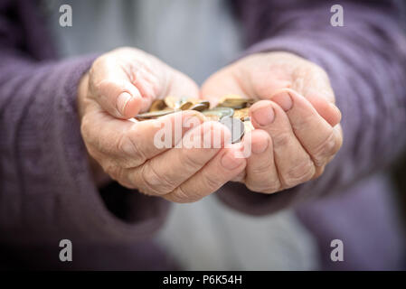 Soldi, monete, la nonna sulle pensioni e il concetto di vita minimo - nelle mani di vecchi una manciata di monete. Close up Foto Stock