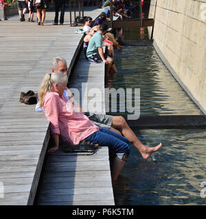 Un giovane non si raffredda in un caldo pomeriggio d'estate nel giardino Lurie river a Chicago il Millennium Park. Foto Stock