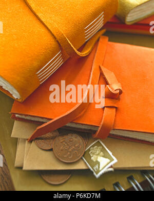 Close-up di arancione e marrone cuoio notebook legato con le vecchie monete di rame e timbro in inglese Foto Stock