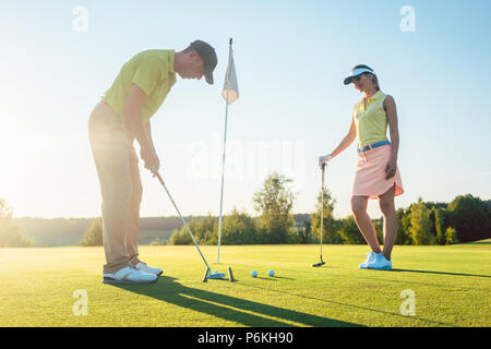 Uomo pronto a colpire la pallina da golf durante l'esercizio con il suo partner di gioco Foto Stock