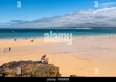 ST IVES, Inghilterra - 18 giugno: l uomo a suonare la chitarra sulla spiaggia di Porthminster, St Ives, su una calda e soleggiata, giorno d'estate. In St Ives, Inghilterra. Il 18 giugno 2018. Foto Stock