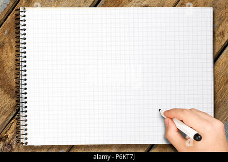 Vista superiore del maschio la scrittura a mano con feltro nero bianco punta squadrata a spirale del notebook su tavola in legno rustico Foto Stock