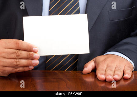Primo piano di imprenditore seduto alla scrivania di contenimento e mostrando grande bianco scheda vuota Foto Stock