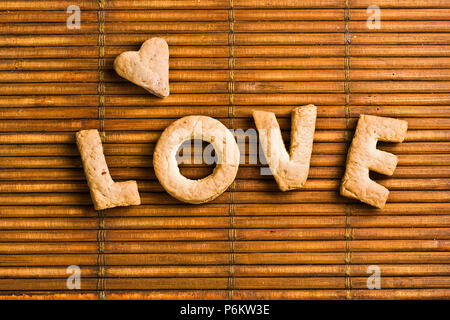 Amore parola composta di biscotti fatti in casa lettere disposte su sfondo di legno Foto Stock